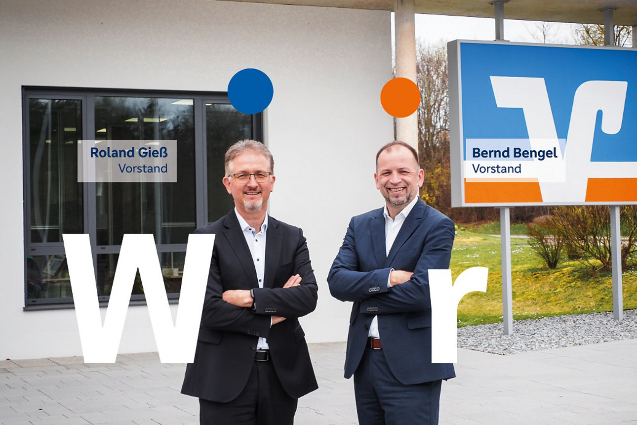 Vorstand Bernd Bengel und Roland Gieß stehen vor einem Verwaltungsgebäude mit VR-Logo im Hintergrund