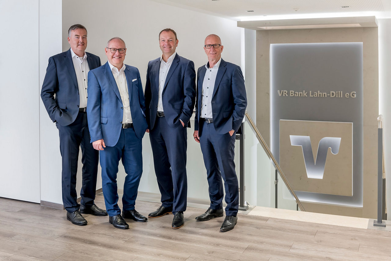 Der Vorstand steht in der Hauptstelle Biedenkopf vor dem VR Bank Lahn-Dill Logo