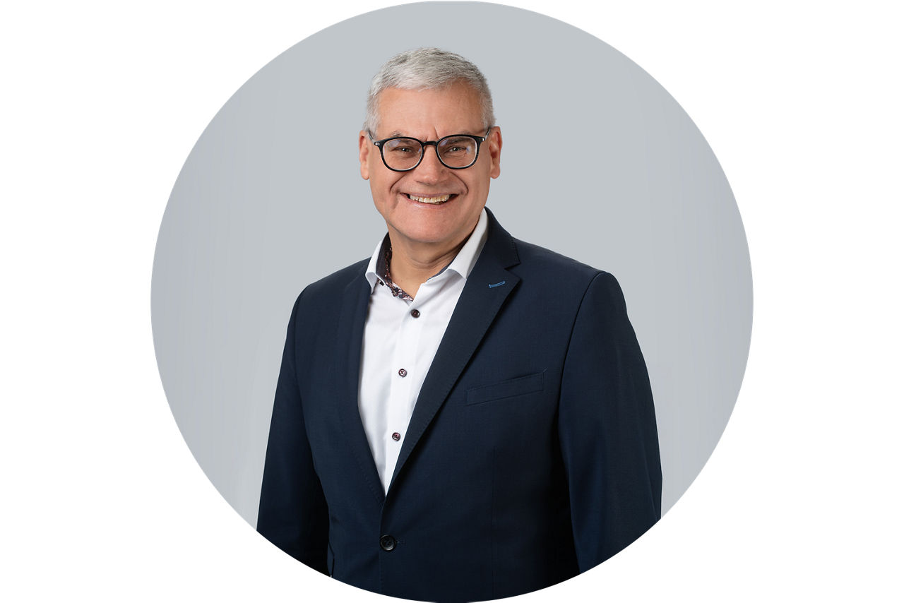 Porträt von Bruno Vey, Vorstand der VR Bank Main-Kinzig-Buedingen eG, vor grauem Hintergrund in dunklem Anzug und weißem Hemd.
