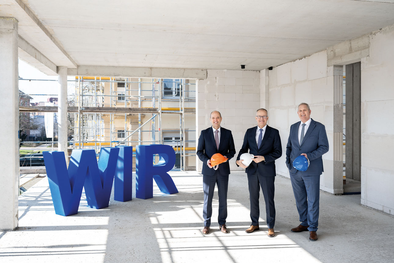 Die Vorstände der Vereinigten VR Bank Kur- und Rheinpfalz stehen in einem Rohbau