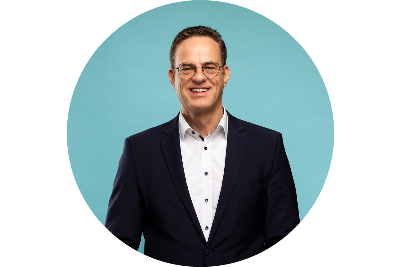 Porträt von Torsten Hopf, Vorstand der VR Bank Fulda eG, vor hellblauem Hintergrund in dunklem Anzug und weißem Hemd.