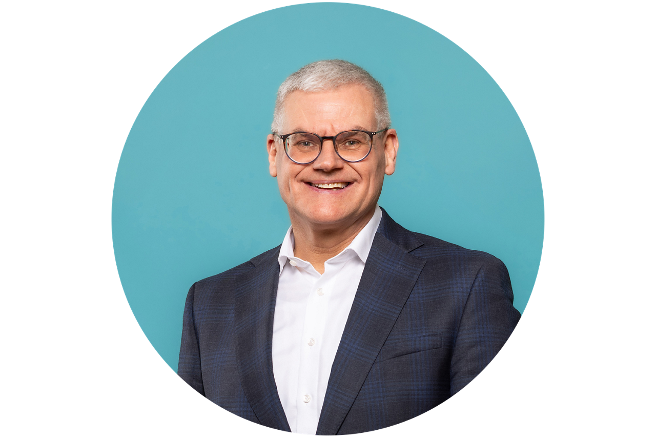 Porträt von Bruno Vey, Vorstand der VR RegionalBank, vor hellblauem Hintergrund in dunklem Anzug und weißem Hemd.