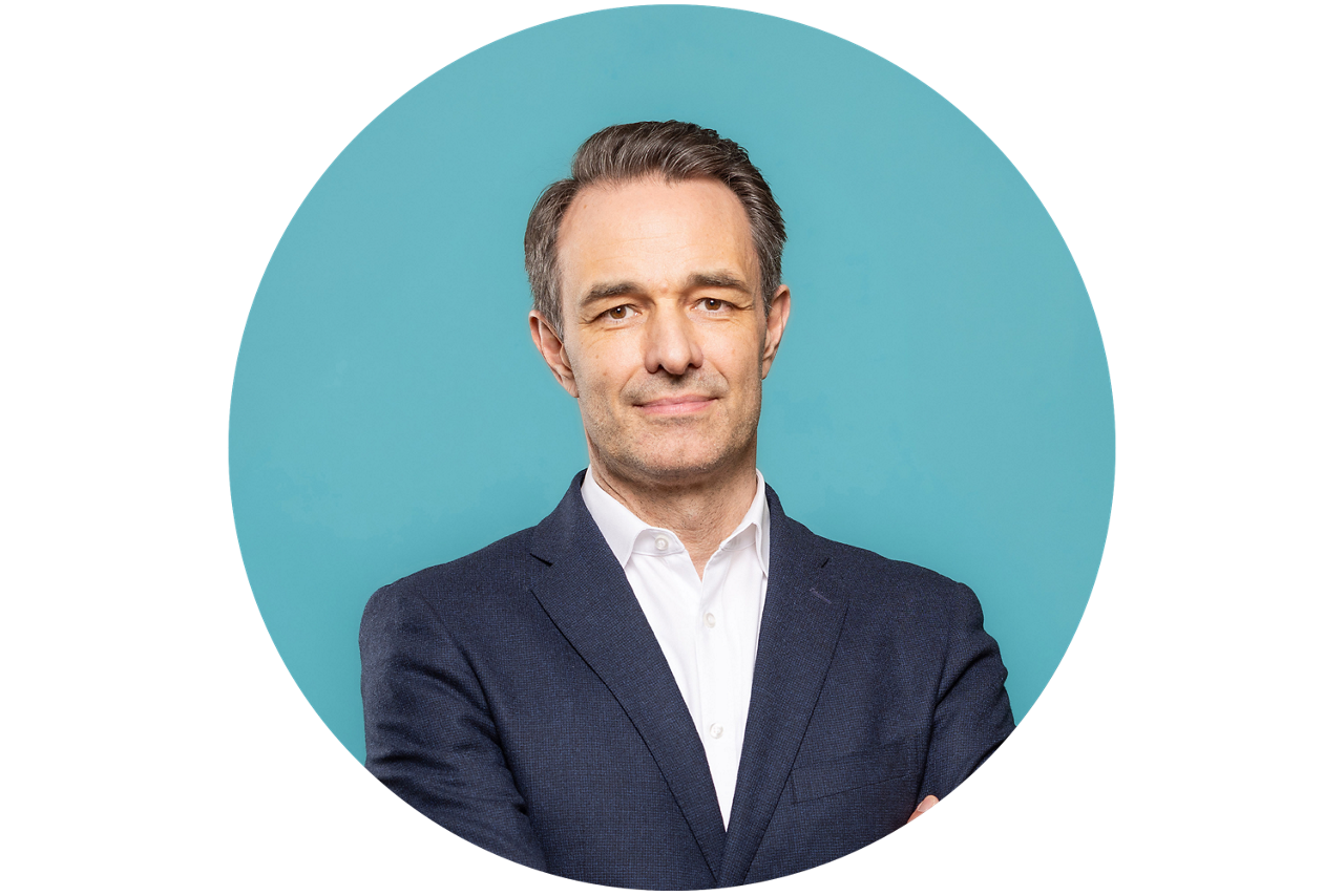 Porträt von Lars Schurich, Vorstand der VR RegionalBank, vor hellblauem Hintergrund in dunklem Anzug und weißem Hemd.