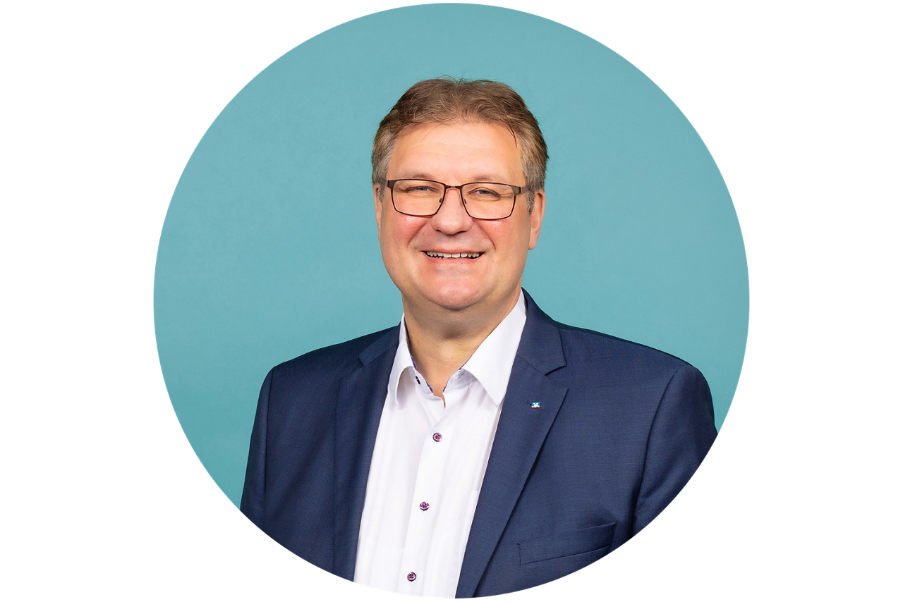 Porträt von Thomas Sälzer, Vorstand der VR Bank Fulda eG, vor hellblauem Hintergrund in dunklem Anzug und weißem Hemd.
