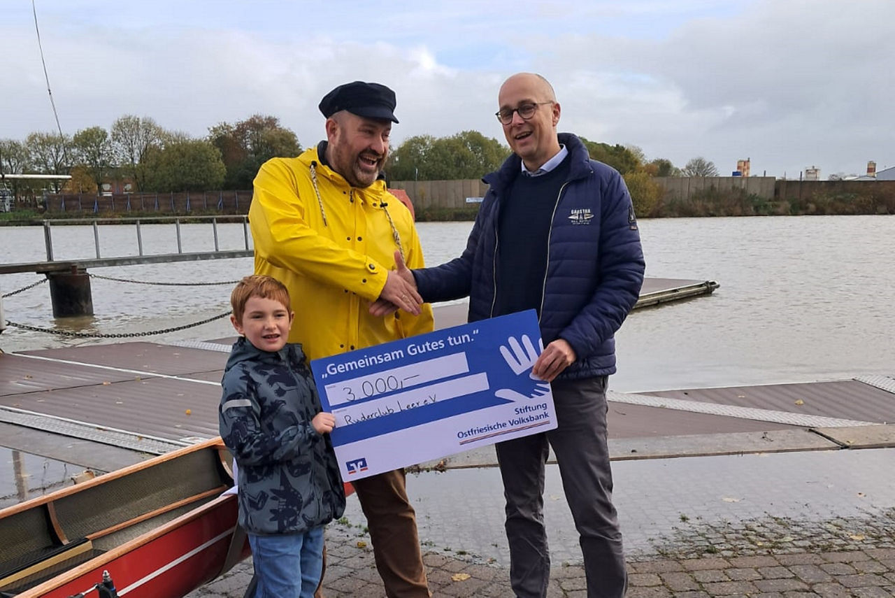 Vorstandsmitglied Guido Mülder steht mit einem Spendenscheck vor dem neuen Ruderboot