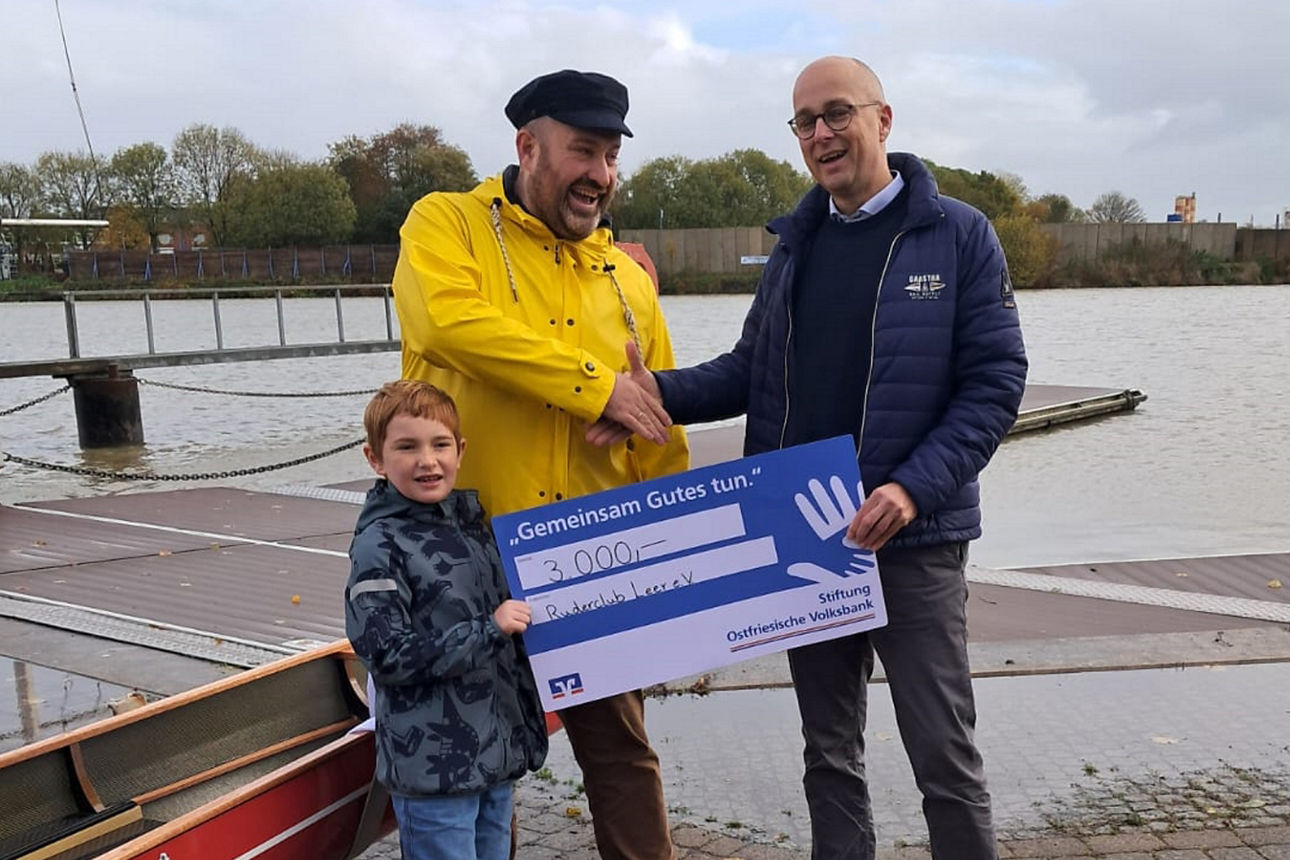 Vorstandsmitglied Guido Mülder steht mit einem Spendenscheck vor dem neuen Ruderboot