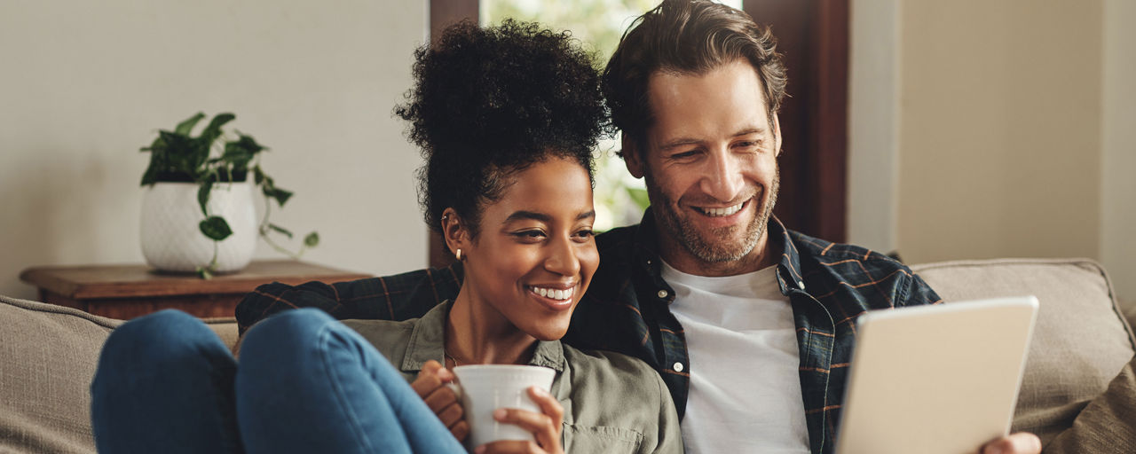 Mann mit Tablet und Frau mit Kaffee auf dem Sofa
