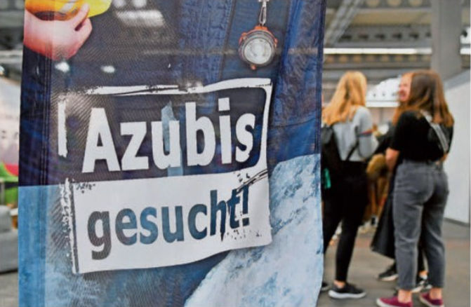 Ein Transparent mit der Aufschrift „Azubis gesucht“ wird auf einer Jobmesse gezeigt.