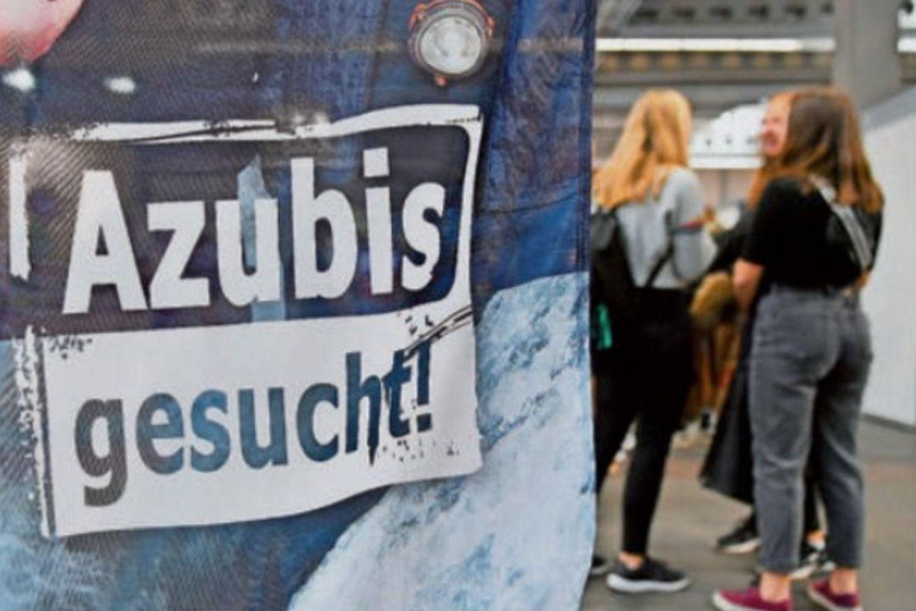 Ein Transparent mit der Aufschrift „Azubis gesucht“ wird auf einer Jobmesse gezeigt.