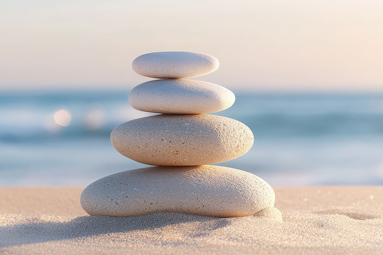 Ein Stapel Steine auf einem Sandstrand, mit Blick auf das Meer und ein Gewässer