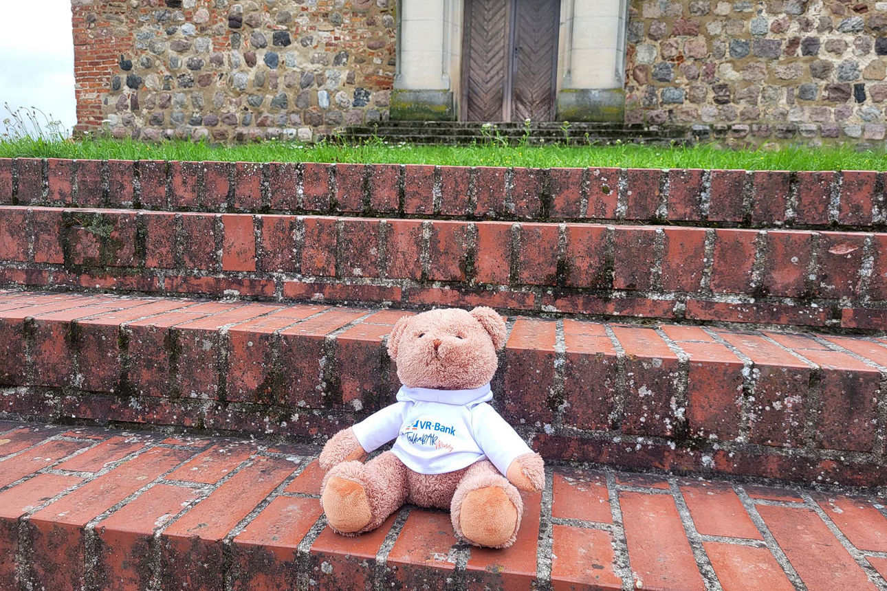 Treddybär sitzt auf einer Steintreppe draußen