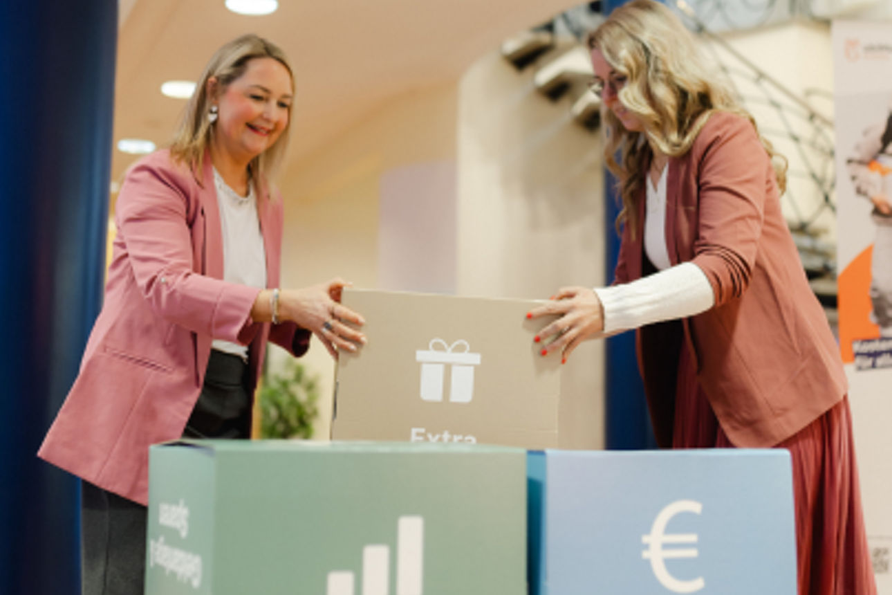 Zwei Personen sitzen entspannt in einem Wohnzimmer nebeneinander und arbeiten jeweils mit einem Tablet.