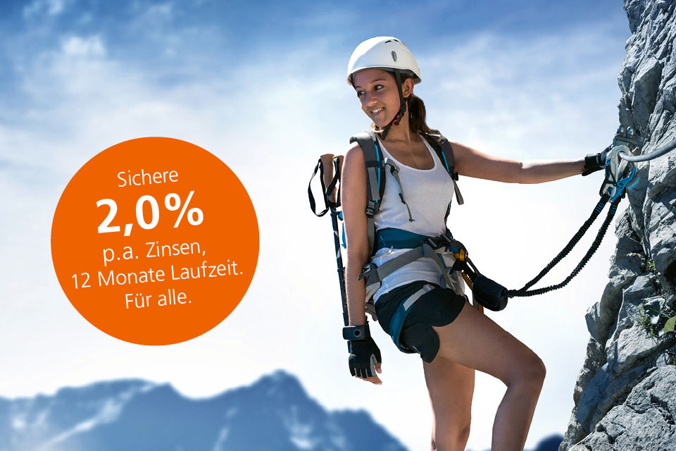 Eine junge Frau ist auf einem Klettersteig unterwegs und blickt lächeln in Richtung Tal