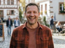 KI-generiertes Porträt eines lächelnden Mannes in einer Altstadtgasse.