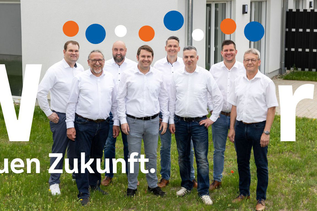 Das Team der Mobilen Baufinanzierungsberater steht vor einem Neubau