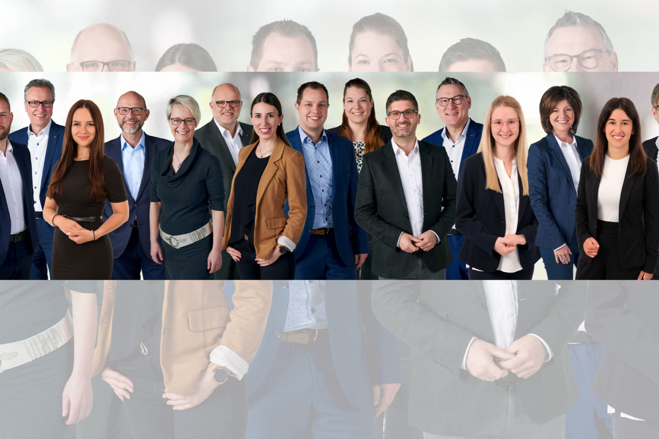Eine Gruppe von Personen in formeller Kleidung steht zusammen vor einem neutralen Hintergrund.
