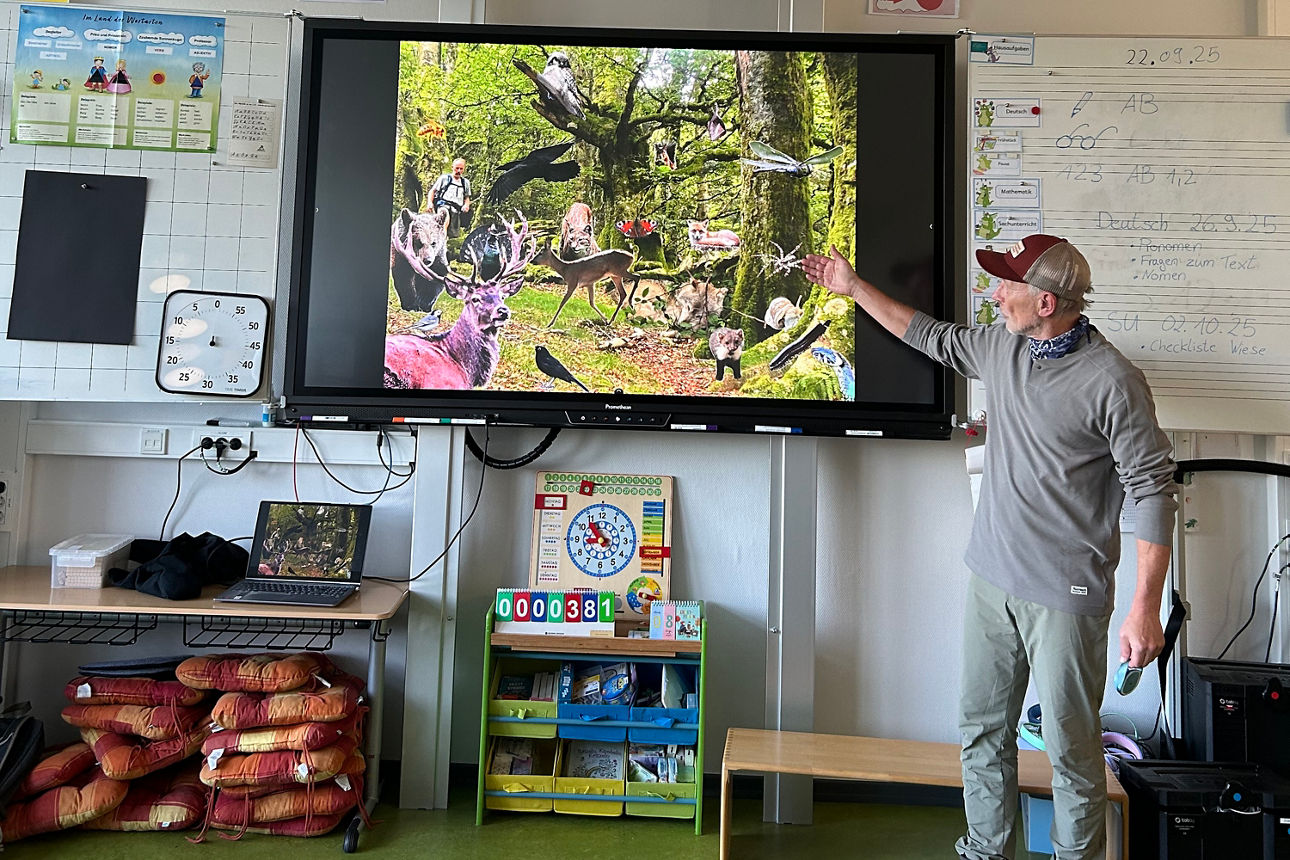 WWF Schulaktion, ein Mann zeigt auf einer Leinwand Waldtiere