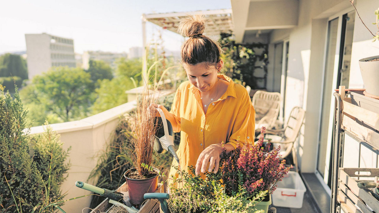 Frau giesst Blumen auf ihrem Balkon