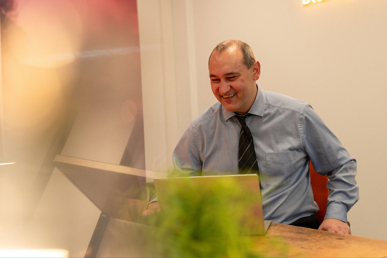 Ein Mann, der an einem Schreibtsich mit Laptop sitzt