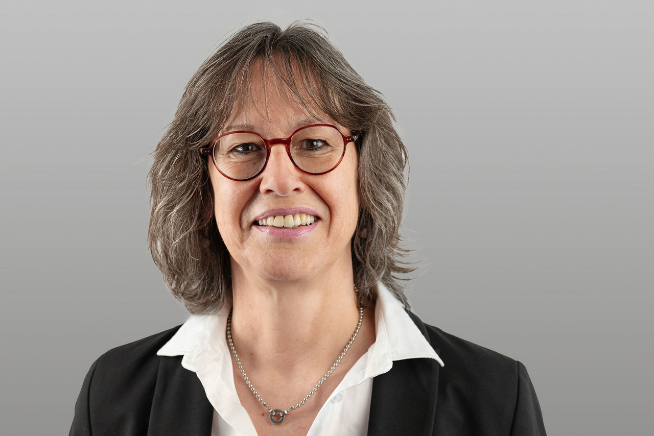 Firmenkundenberaterin Claudia Wahlen vor grauem Hintergrund