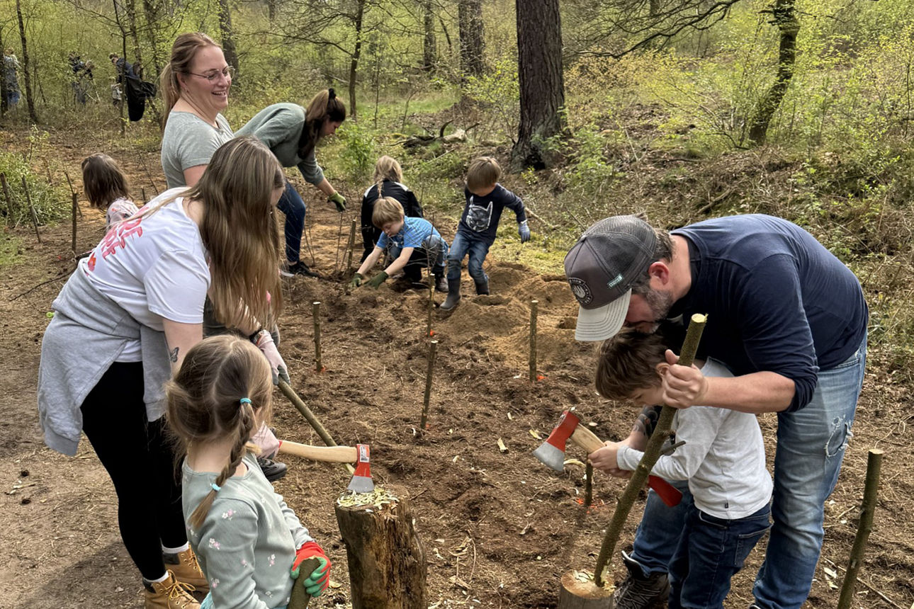 Hölzer werden angespitzt, damit daraus eine Naturmauer entstehen kann.