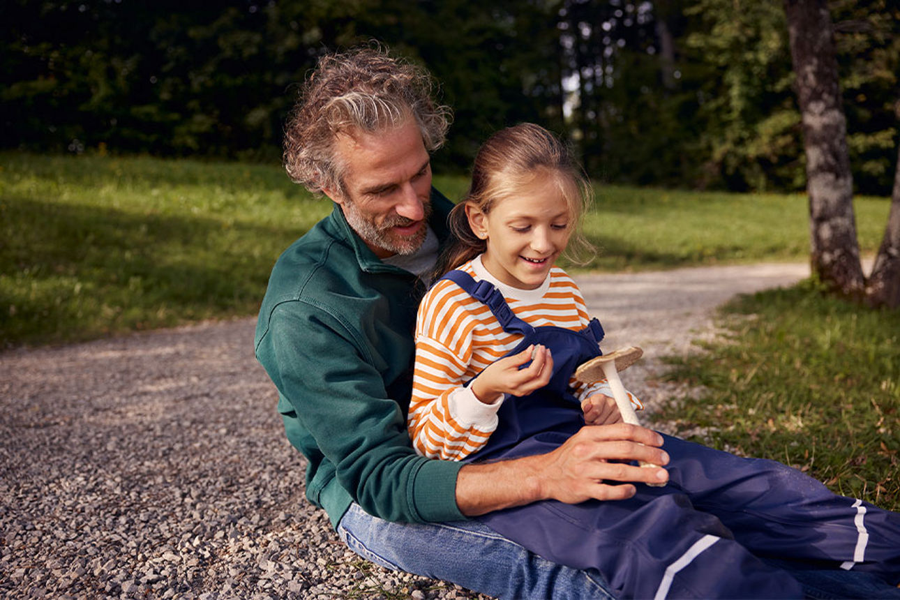 Vater und Tochter betrachten einen Pilz