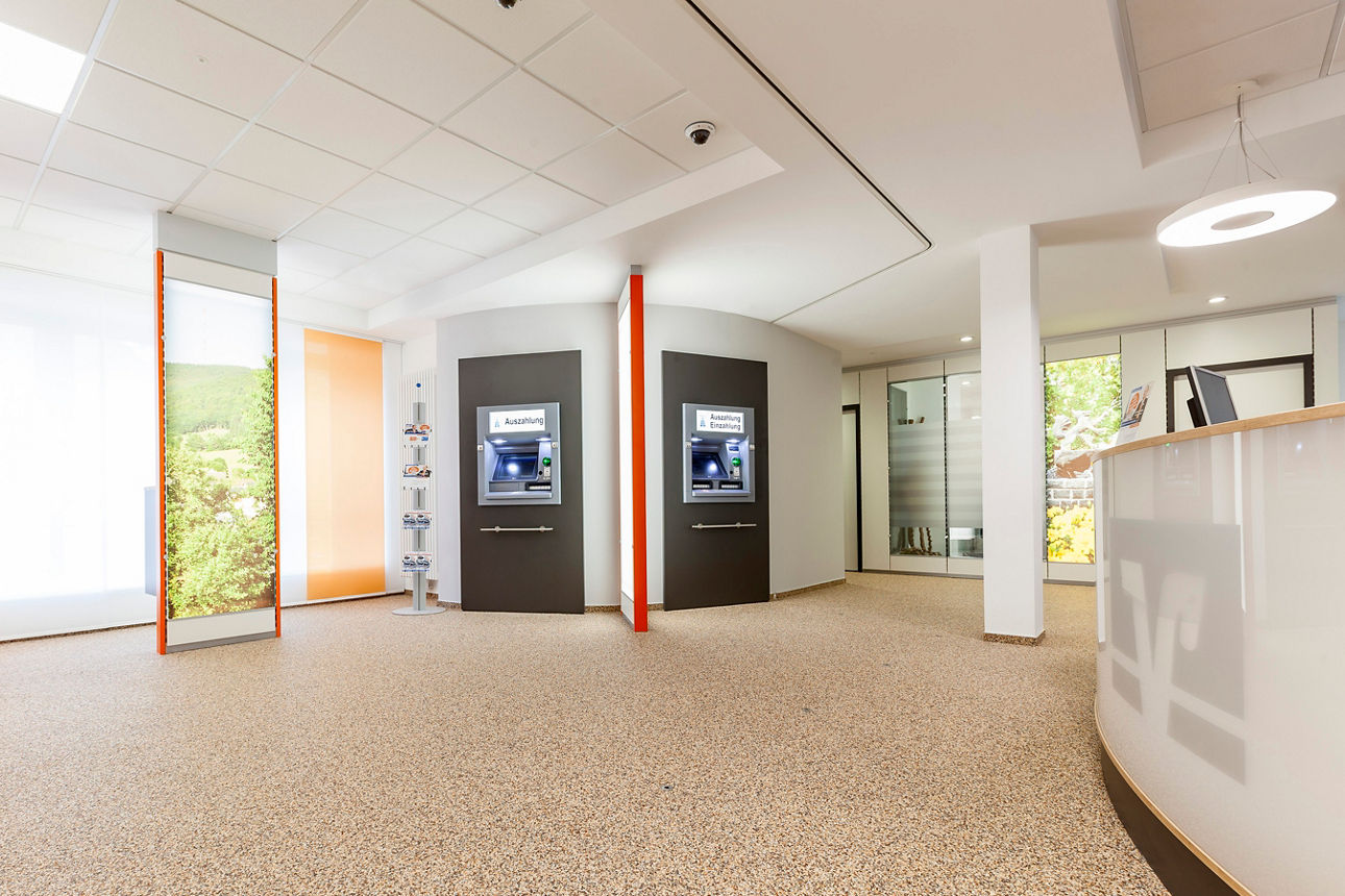 Heller Empfangsbereich mit zwei schwarzen Automaten an der Wand und einem weißen Empfangstresen rechts
