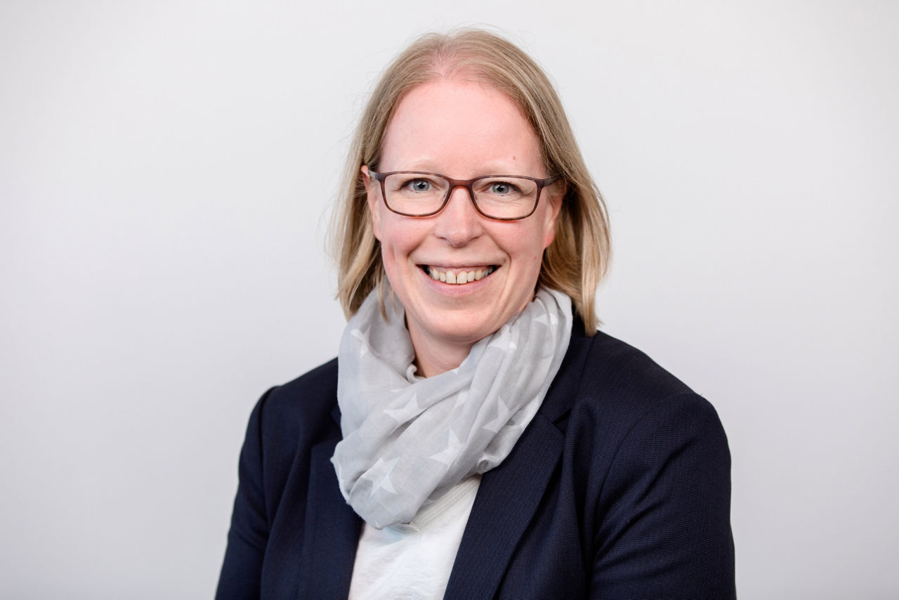 Eine lächelnder Frau schaut in die Kamera.