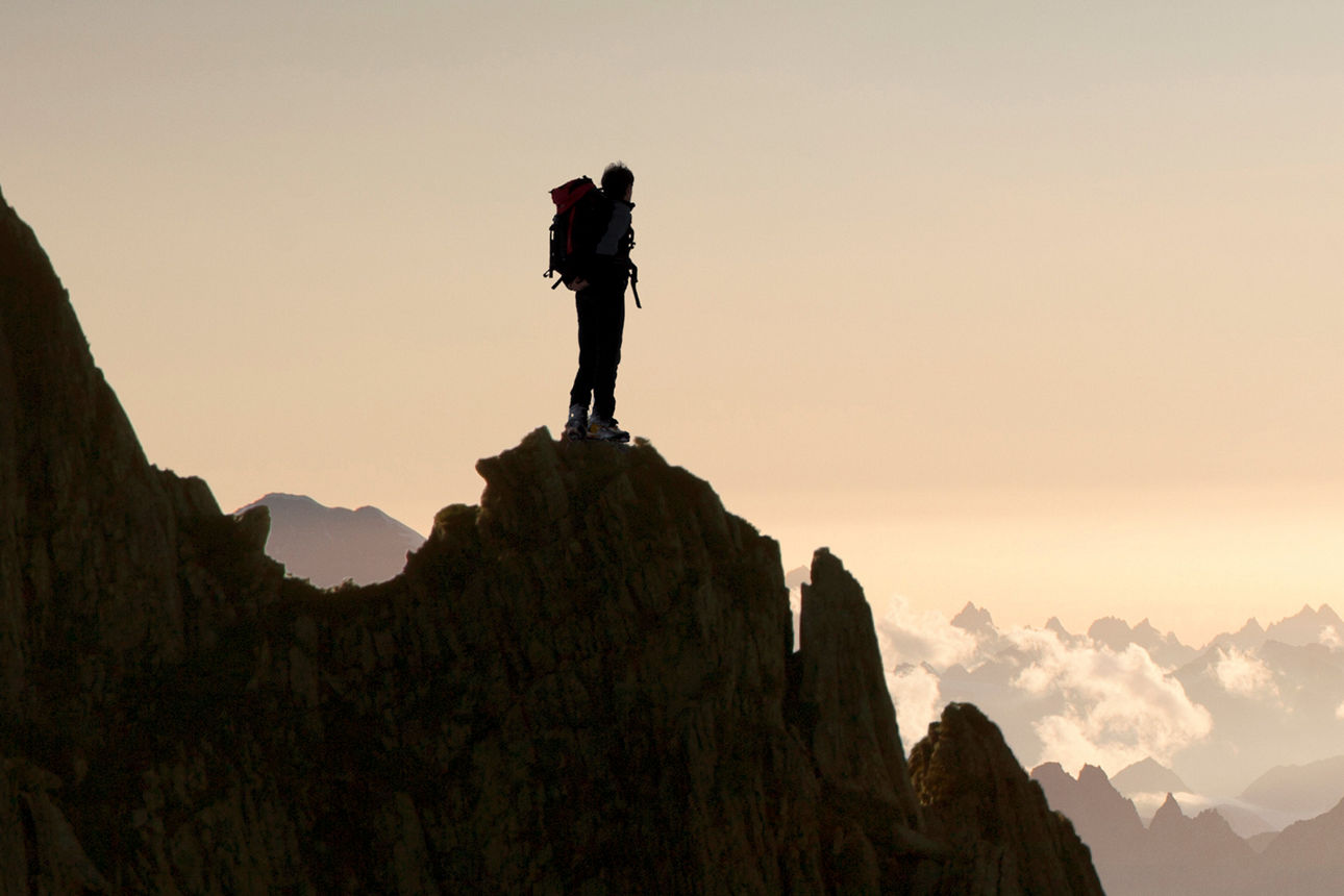 Wanderer steht auf Berggipfel