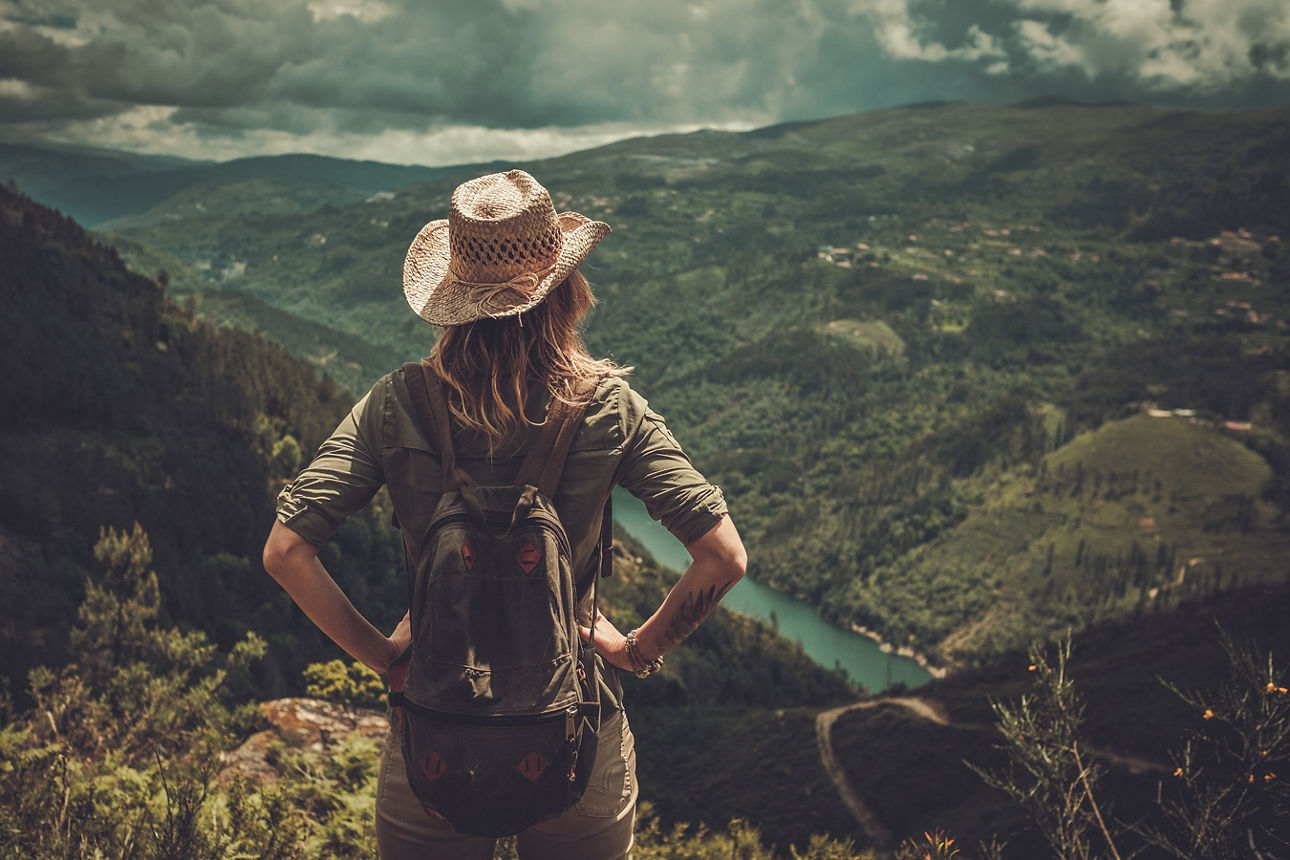 Eine Wanderin genießt den Ausblick über Berge und Täler beim Wandern