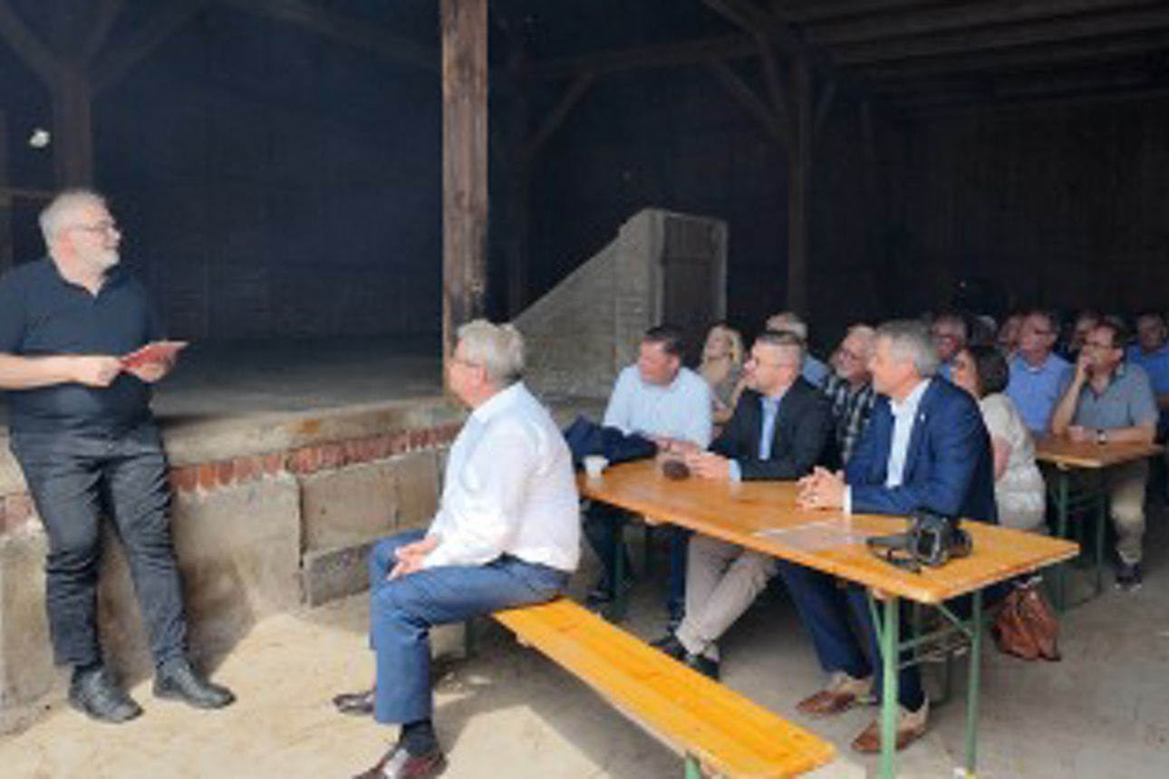 Menschen auf Bänken lauschen einem Vortrag in der Scheune