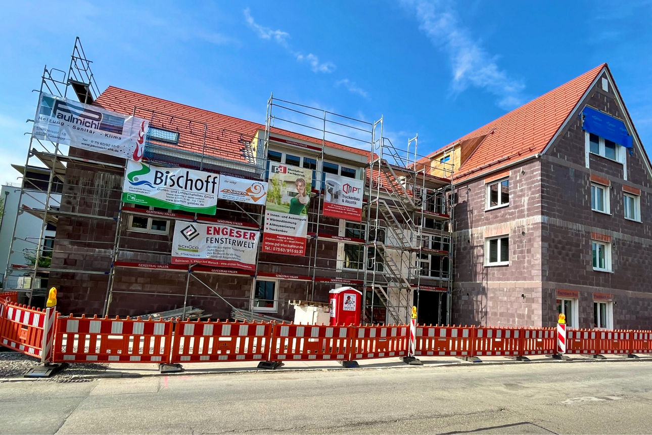 Rohbau eines Mehrfamilienhauses in Wangen im Allgäu. Es sind Baugerüste um das Haus aufgestellt.