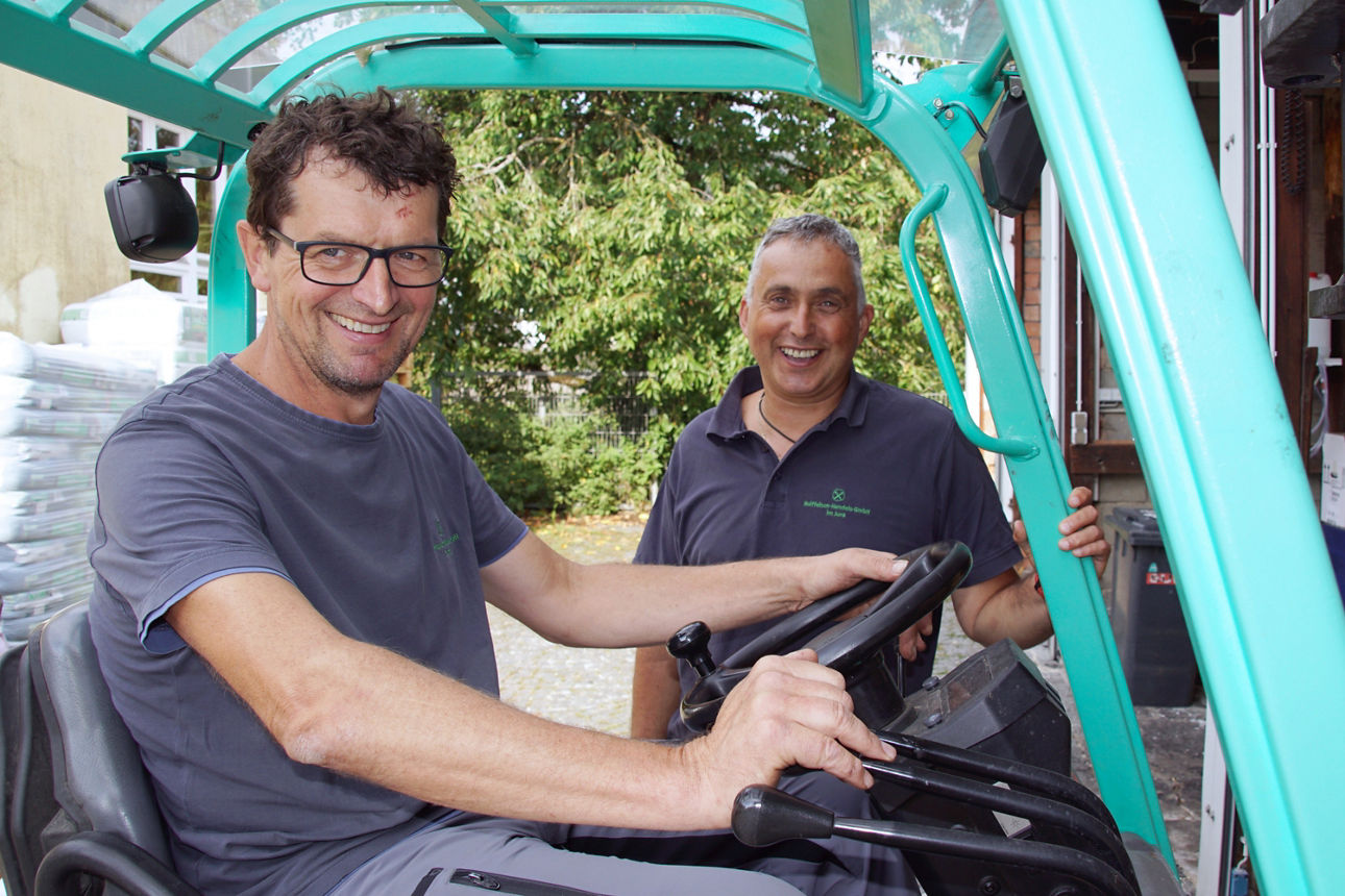 Mitarbeiter der Raiffeisen-Waren-Markt GmbH Neumarkt-Roth auf und neben einem Gabelstabler