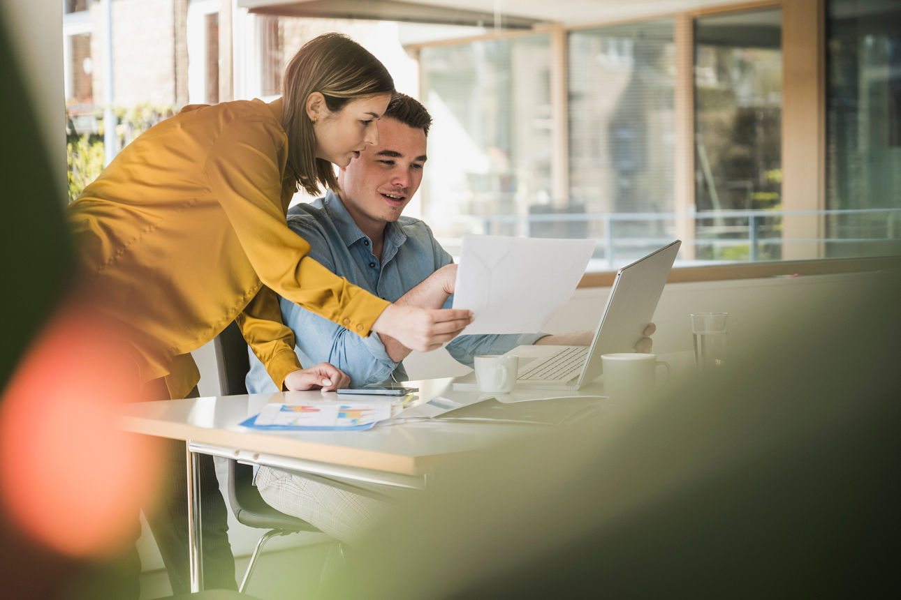 Mann und Frau schauen gemeinsam lächelnd auf einen Laptop