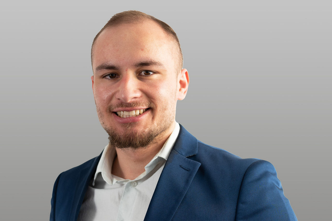 Kundenberater Dominik Wasilewski vor grauen Hintergrund
