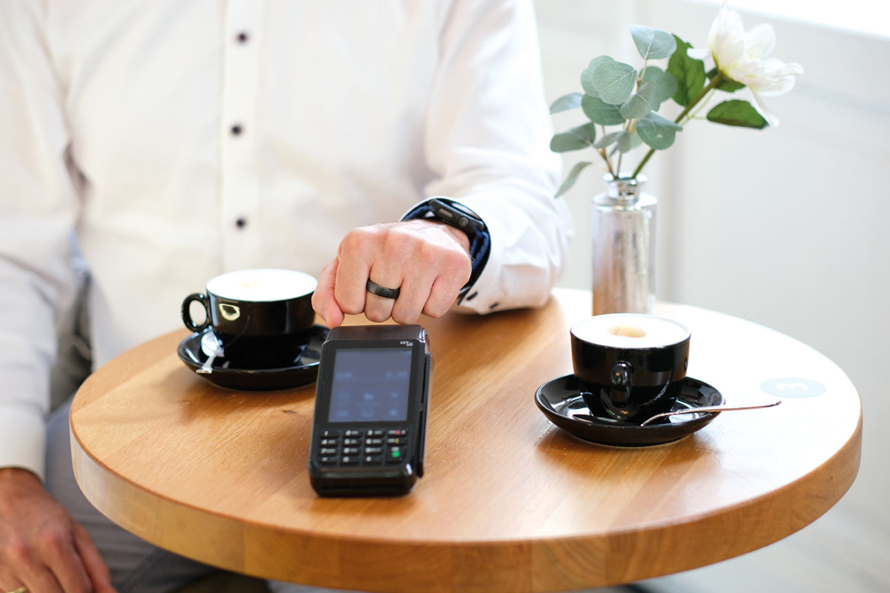 Hand vor einem Kartenlesegerät mit einem Bezahlring