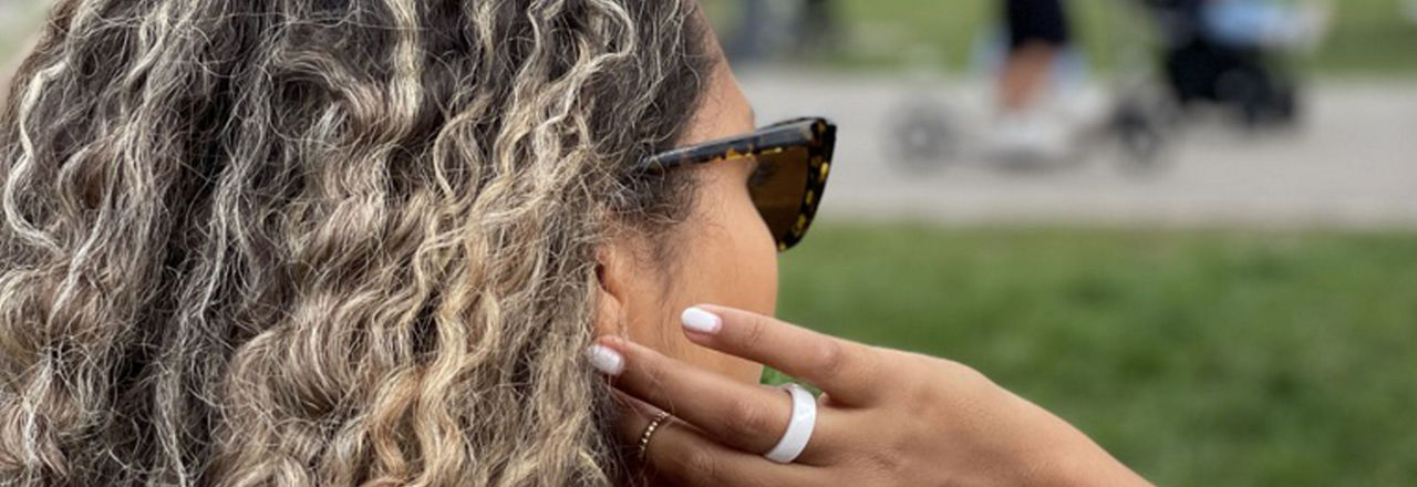 Eine Frau fasst sich in die Haare und hat einen Bezahlring am Finger