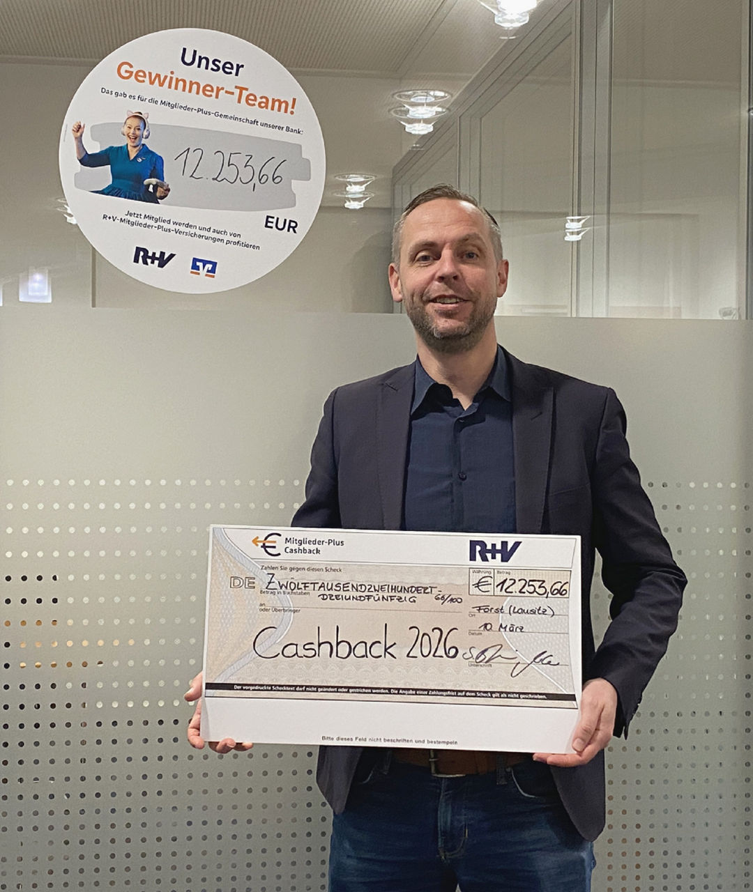 Sten Byhain hält den Scheck für die R+V-Cashback in den Händen