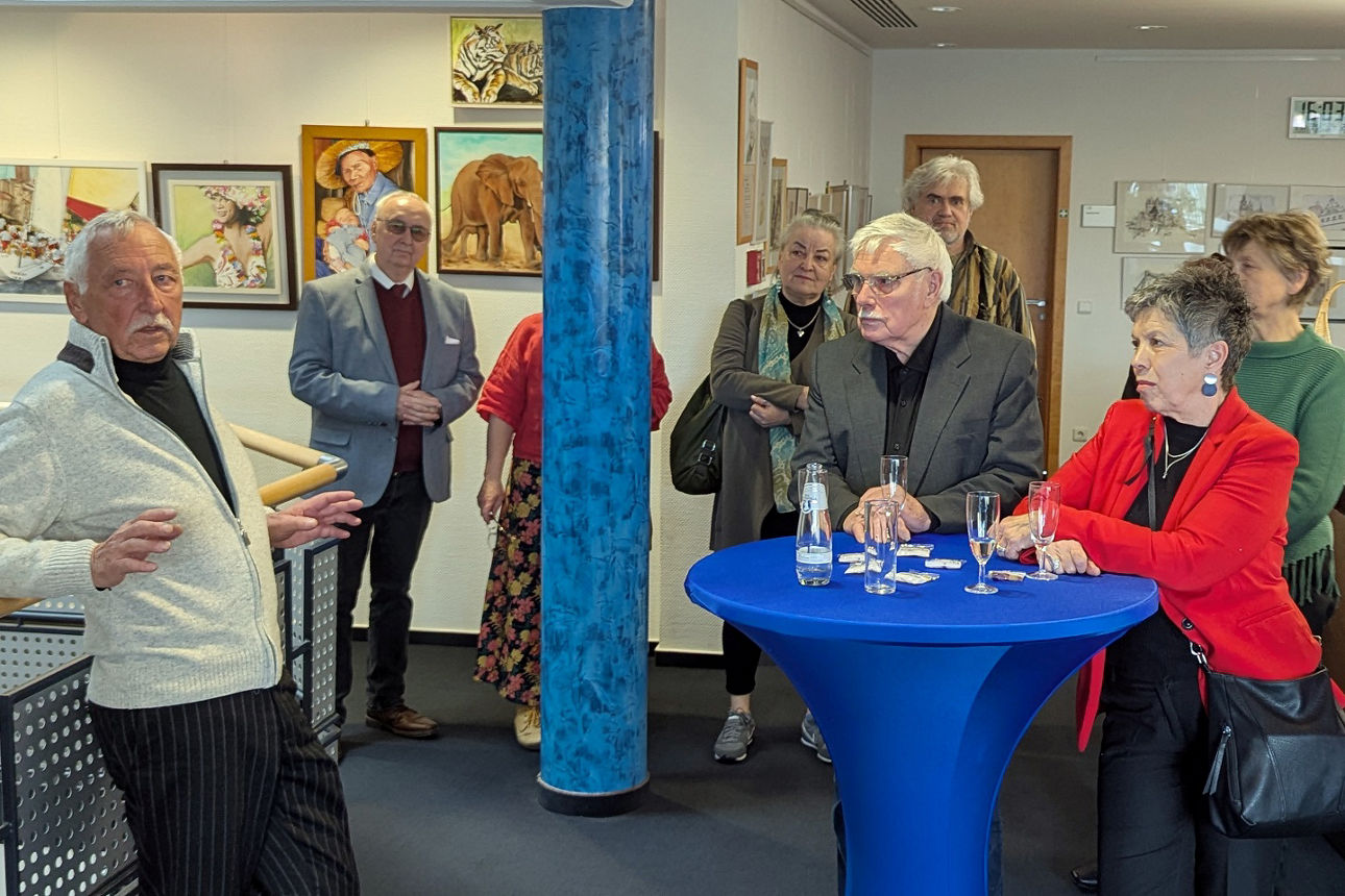 Menschen stehen im Foyer und lauschen den Worten des Malers Wolfgang Möller