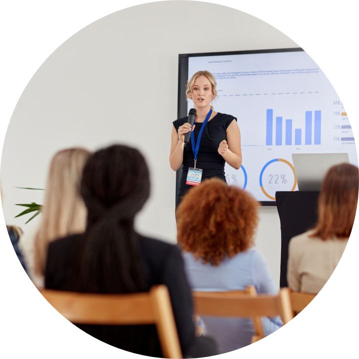 Frau hält eine Vortrag vor sitzendem Publikum