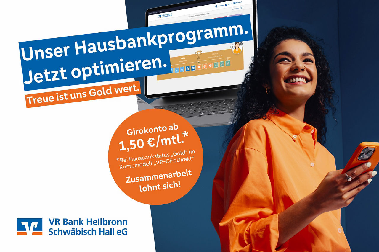Eine Frau in orangener Bluse lächelt mit Smartphone in der Hand und im Hintergrund ist ein Laptop mit einer Anzeige des Hausbankprogramms zu sehen. Auf dem Bild steht der Slogan: Unser Hausbankprogramm. Jetzt optimieren.