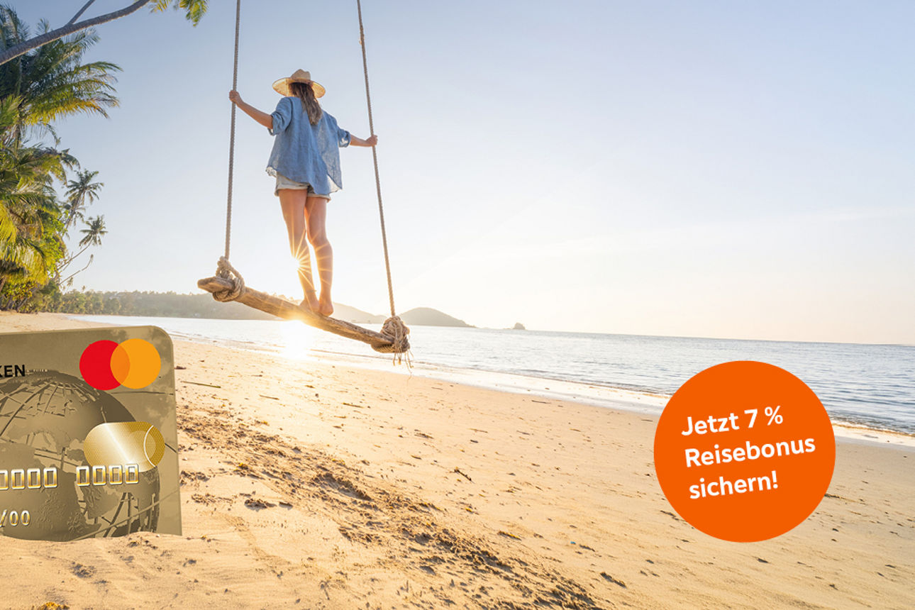 Frau stehend auf einer Schaukel unter Palmen am Strand, im Vordergrund steckt eine GoldCard im Sand.