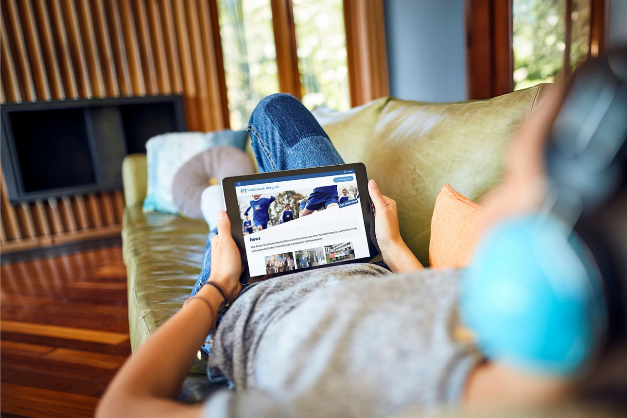 Mädchen liegt auf dem Sofa und schaut auf ein iPad