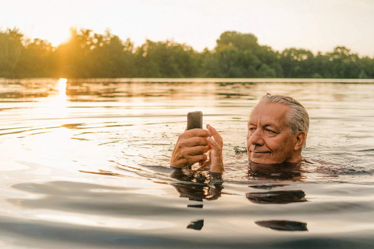 Älterer Mann im Wasser mit einem SmartPhone