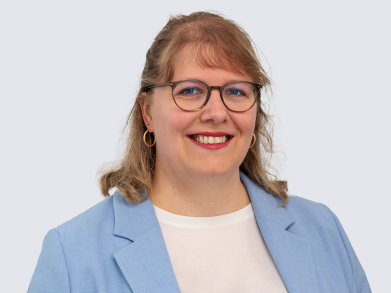Frau mit blonden Haaren und hellblauem Blazer
