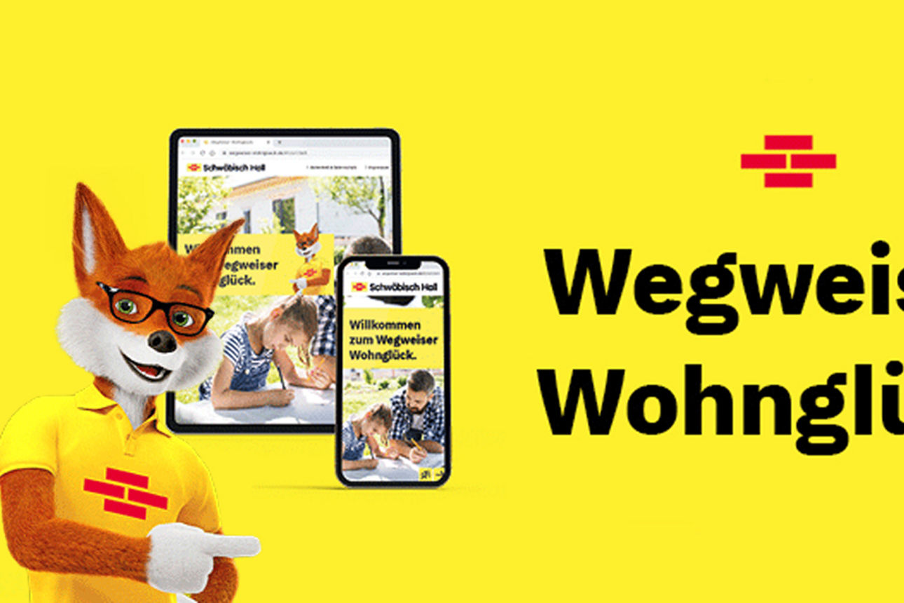 Der Bausparfuchs zeigt auf ein Handy und ein Tablet. Auf denen wird der Wegweiser Wohnglück angezeigt