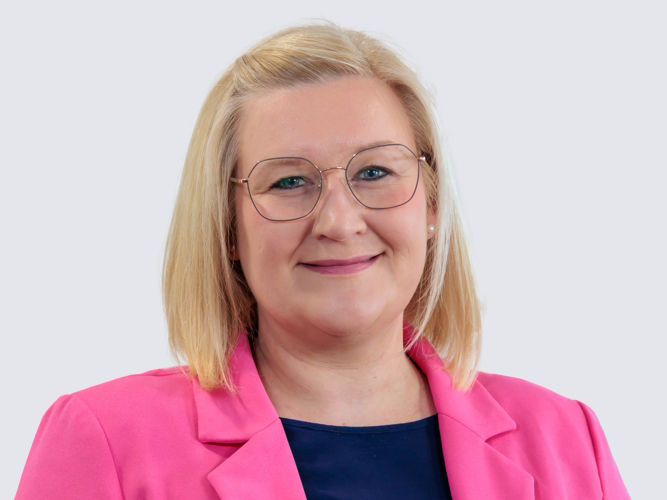 Frau mit blonden Haaren und pinkem Blazer