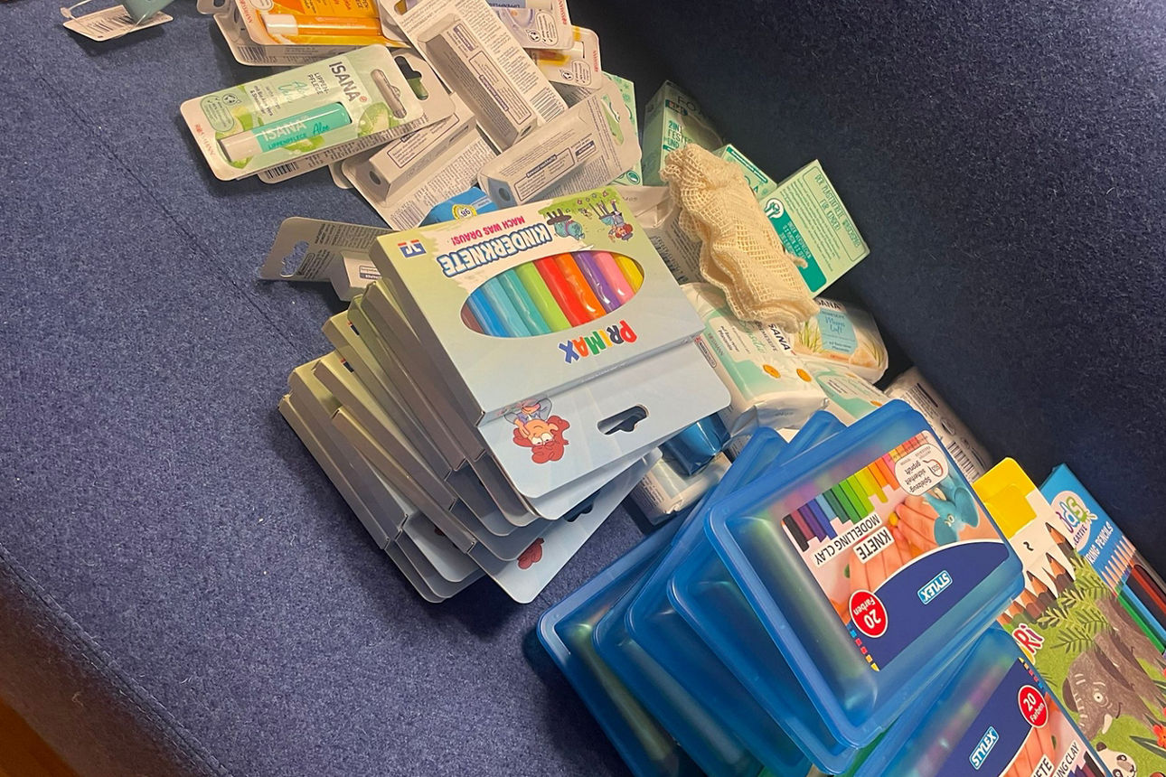 Knete, Stifte und Labellos liegen auf Stapeln auf einer Couch.