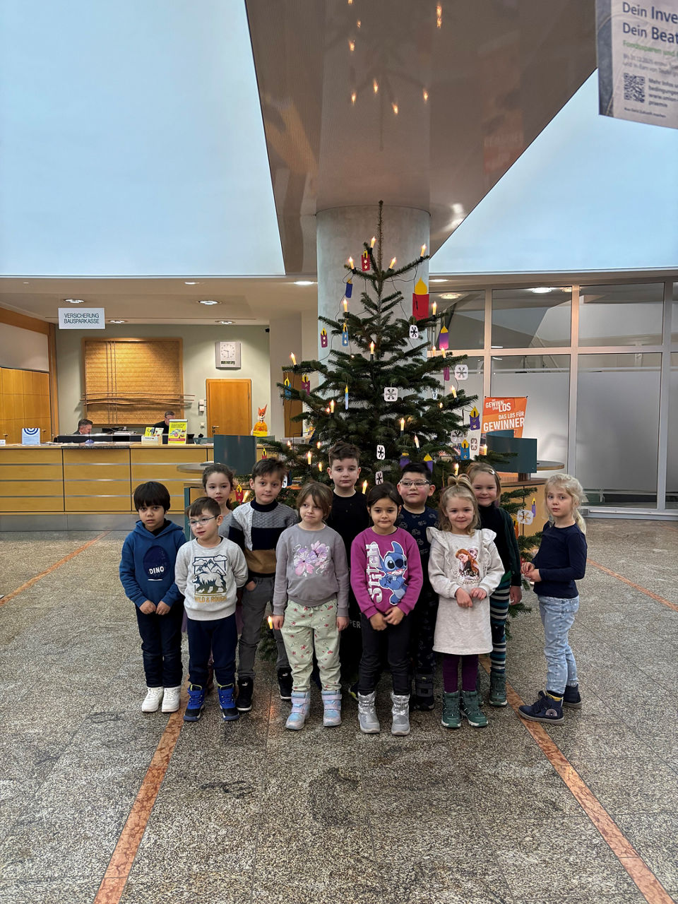 Kindergartenkinder vom Kiga "Heilige Familie" schmücken den Weihnachtsbaum der Bank