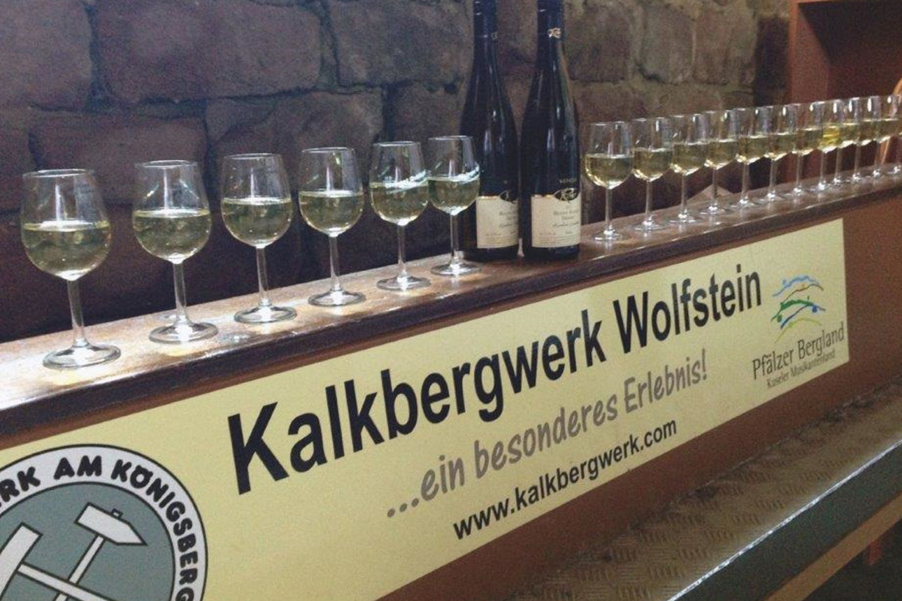 Weingläser und Weinflaschen auf eine Theke mit Plakat Kallkbergwerk Wolfstein